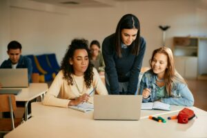 High school teacher assisting her students with e-learning during computer class.