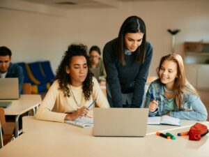 High school teacher assisting her students with e-learning during computer class.
