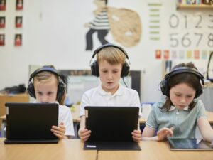Schoolboy and girls listening to headphones in class at primary school