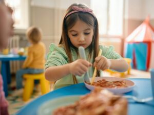 Little girl eating lunch at kindergarten.